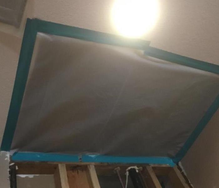 a plastic sheet covering parts of ceiling with blue tape