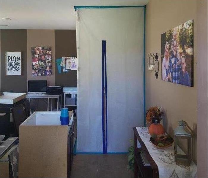 Room, family picture on the wall, furniture. Plastic barriers inside containing mold